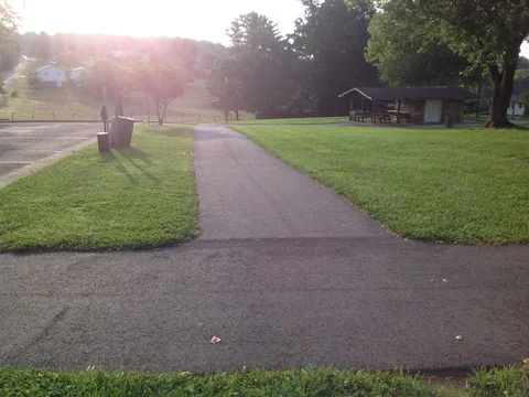 A paved path leading to a picnic shelter in evening light