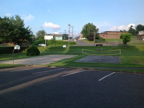 An outdoor basketball court beside a sand volleyball court